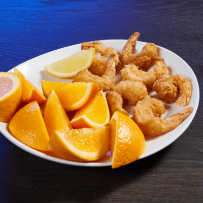 fried shrimp platter of seven on a plate with orange slices